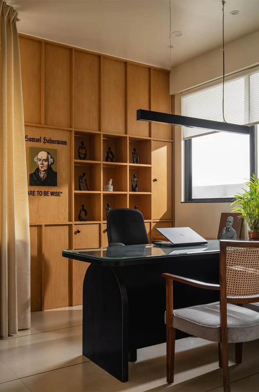 The doctor's room: timber shelving, a black desk and a cane chair