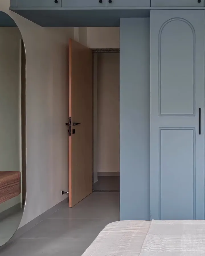 Slate blue wardrobes with arched panels running the length of the bedroom