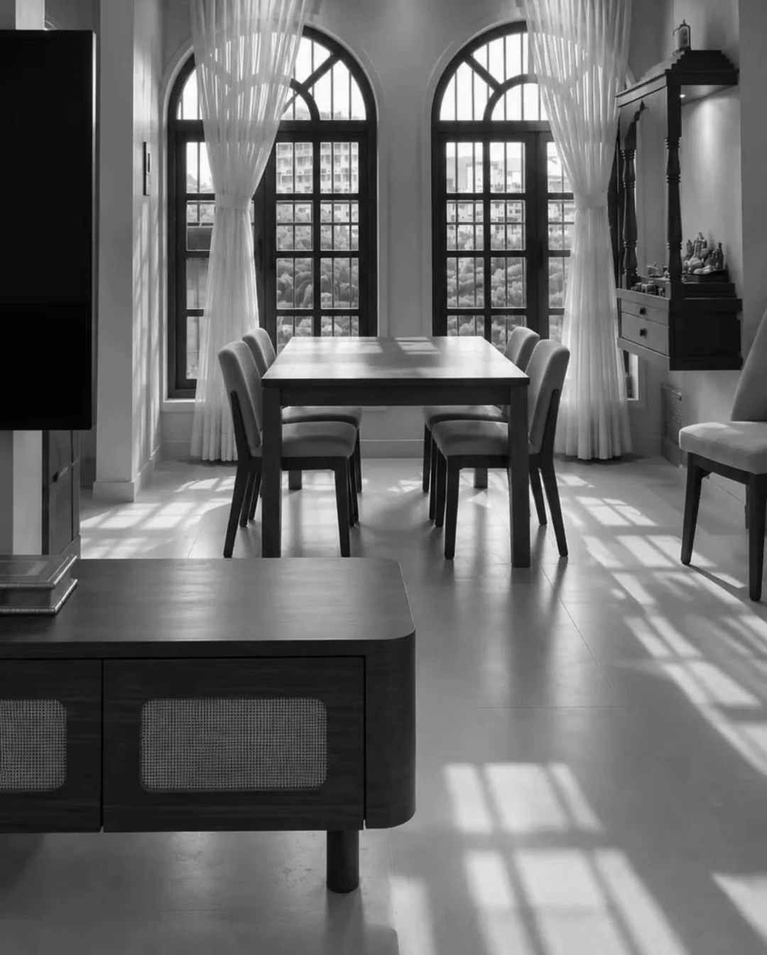 The finished dining room under two arched windows, sheer curtains drawn back, sun across the floor